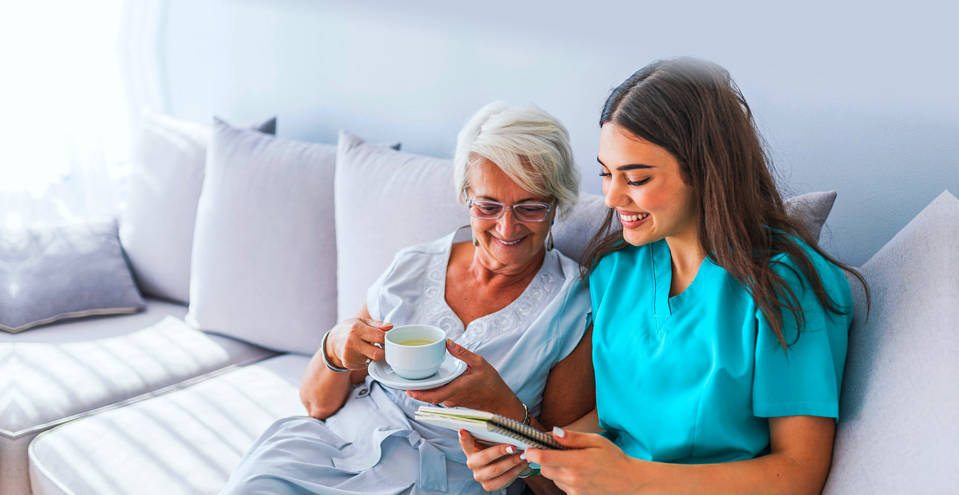 seior woman with female caregiver reading on notebook