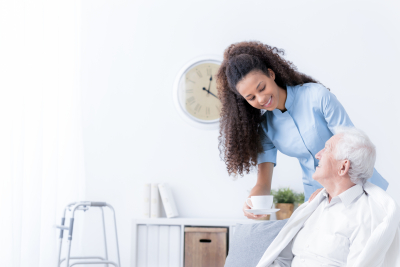 caregiver giving tea to senior man